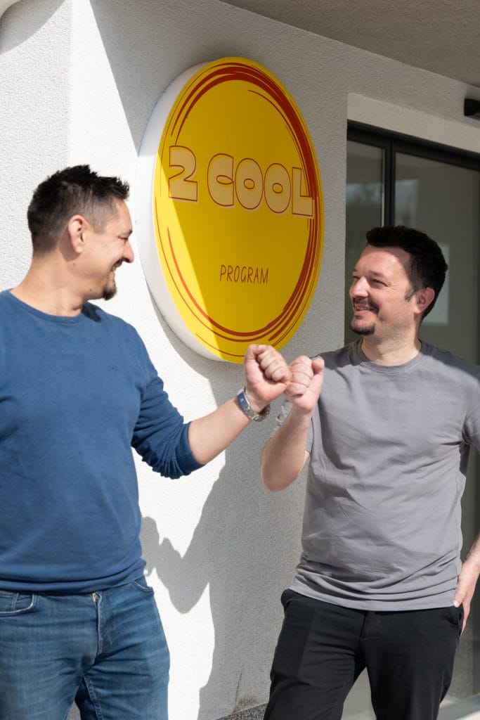 Dva muškarca ispred natpisa '2 Cool Program'.